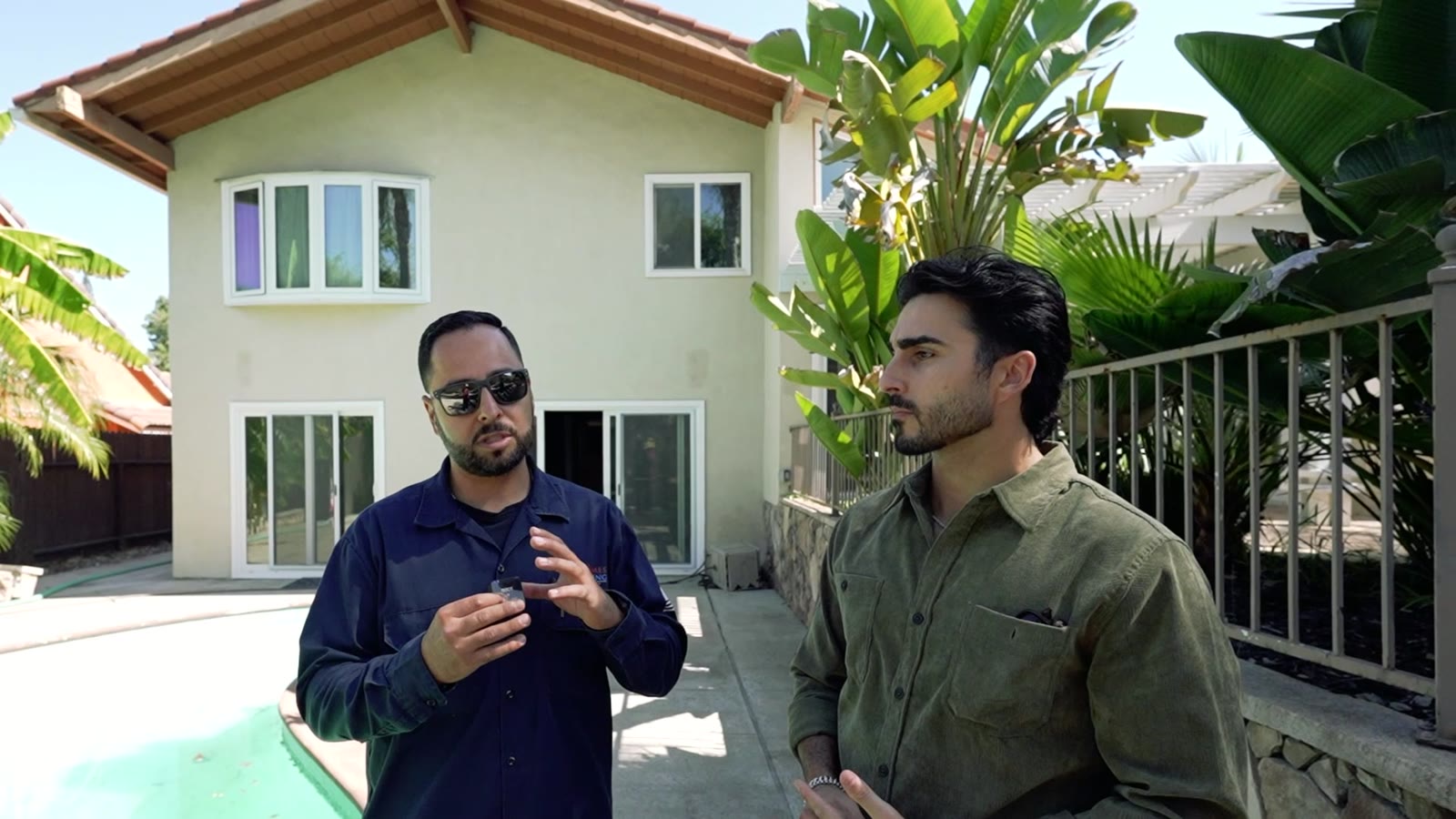 Contractor and host standing in front of a two-story home with a pool during a remodel walkthrough