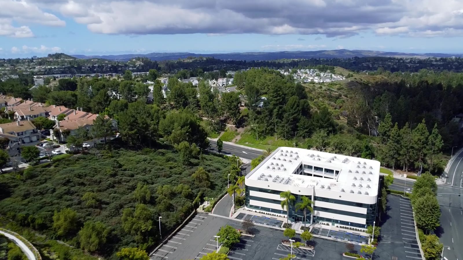 Aerial view of a three-story office building in El Toro surrounded by trees